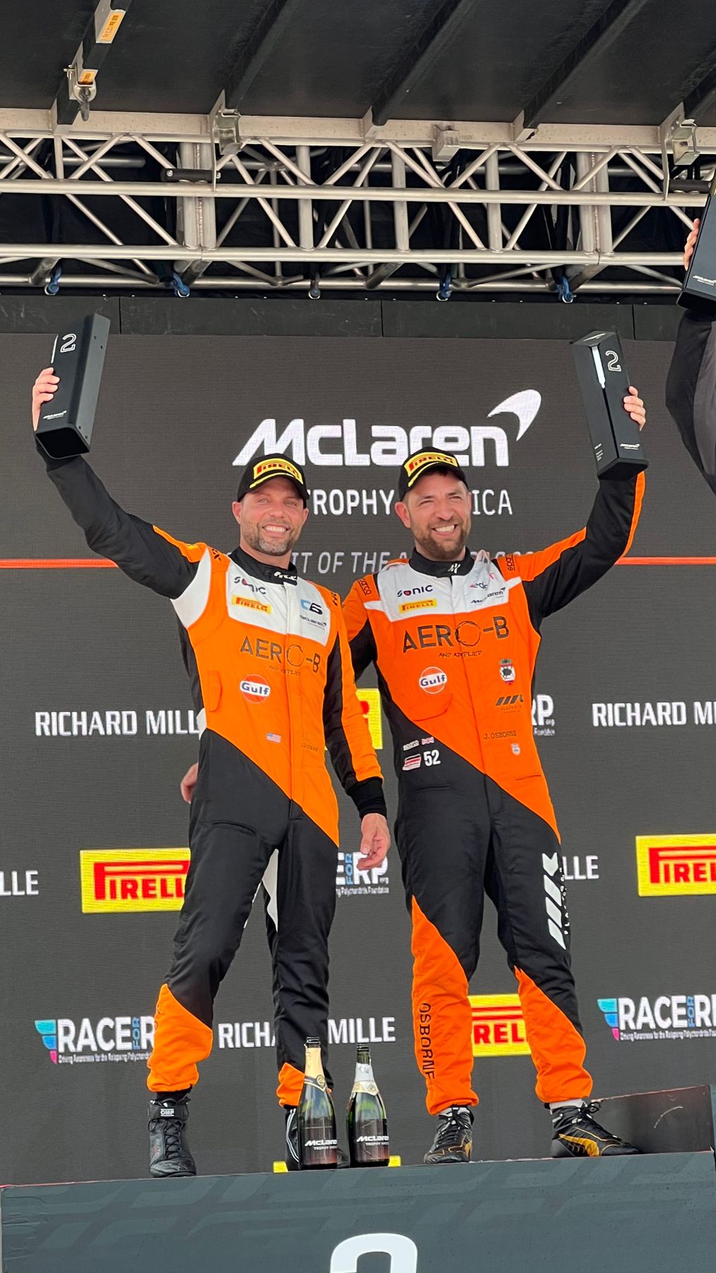 Jason and his co-driver raising 2nd place trophies at Circuit of the Americas
