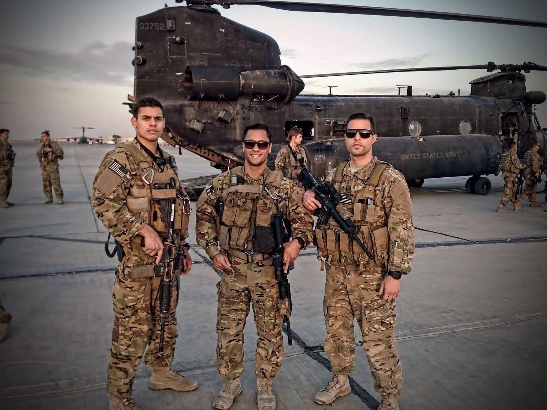 Jason with two fellow soldiers in front of a Chinook helicopter on deployment